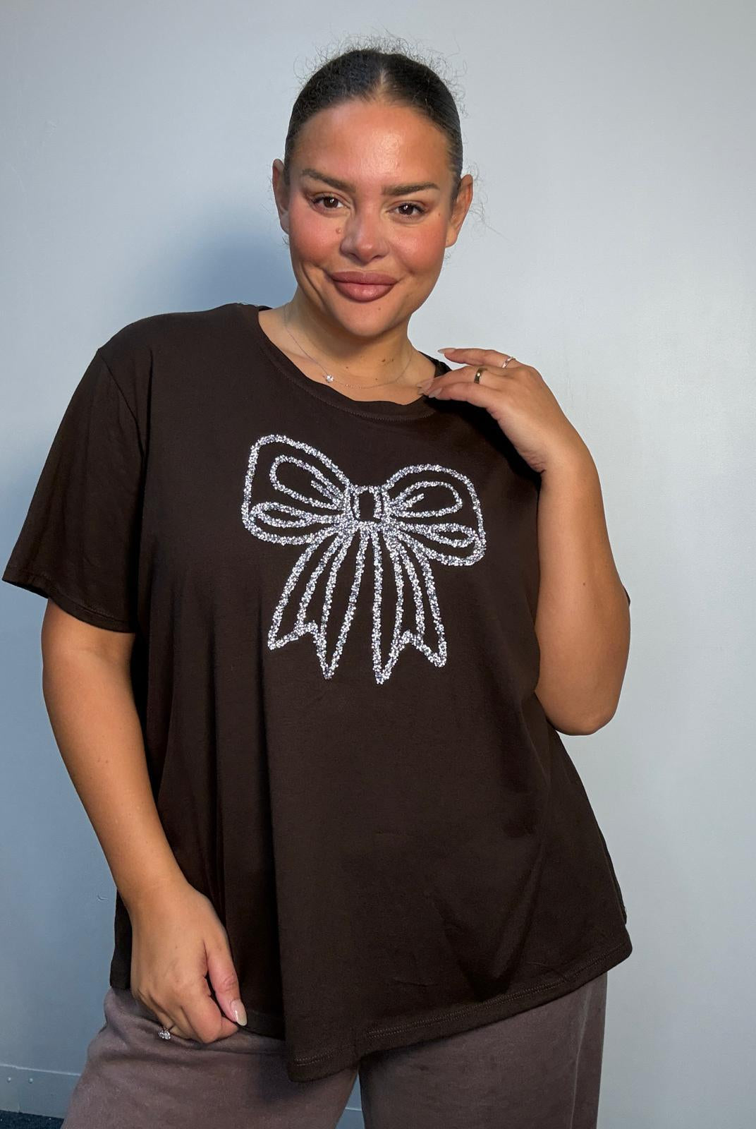 Plus Size Mixed Race Model wearing a brown short sleeve top with bow diamante detail at the front