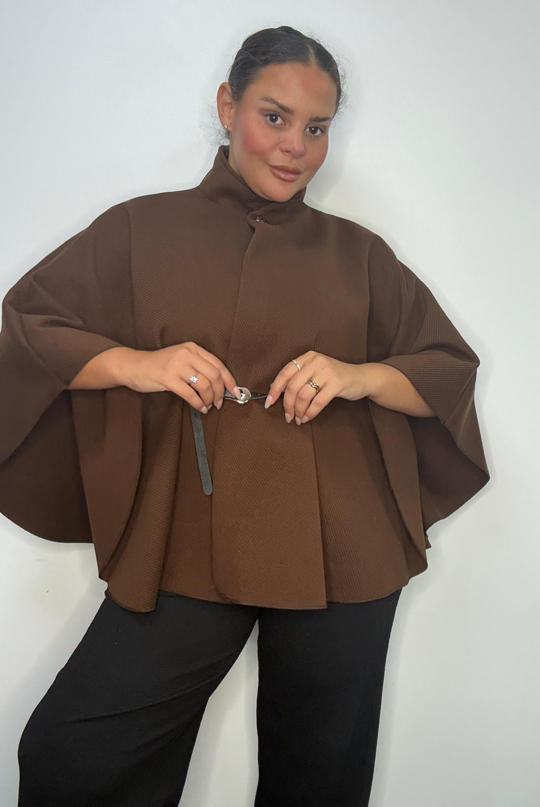 Plus-size model wearing a brown belted cape-style jacket with a high neckline and wide sleeves.