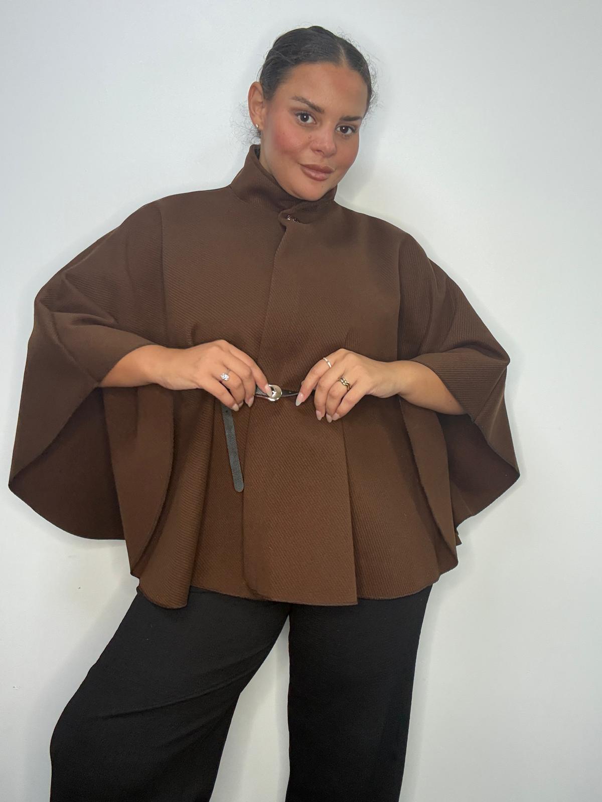 Plus-size model wearing a brown belted cape-style jacket with a high neckline and wide sleeves.