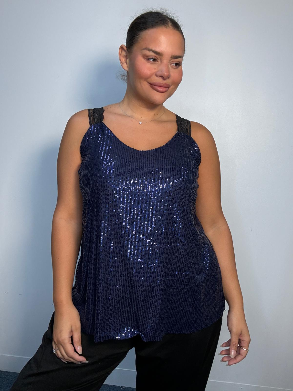 Plus-size model wearing a navy sequin cami top with V-neckline, black lace-look shoulder straps and a relaxed flared hem.