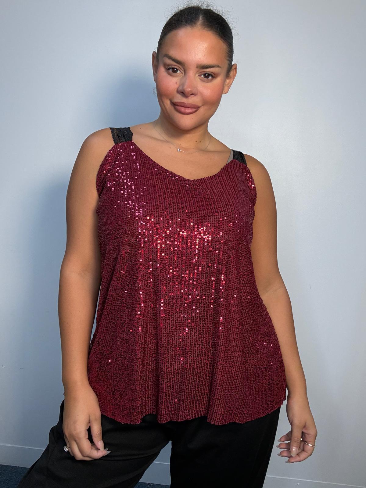 Plus-size model wearing a burgundy sequin cami top with V-neckline, black lace-look shoulder straps and a relaxed flared hem.