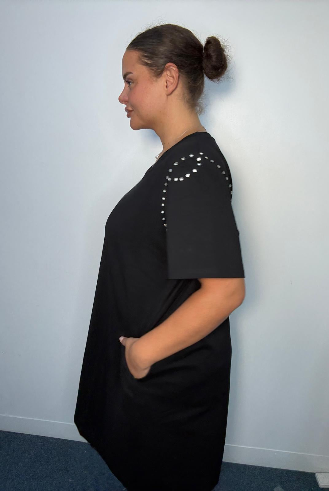 Side view of a black plus-size midi dress featuring diamante-style shoulder detailing, short sleeves and side pocket.