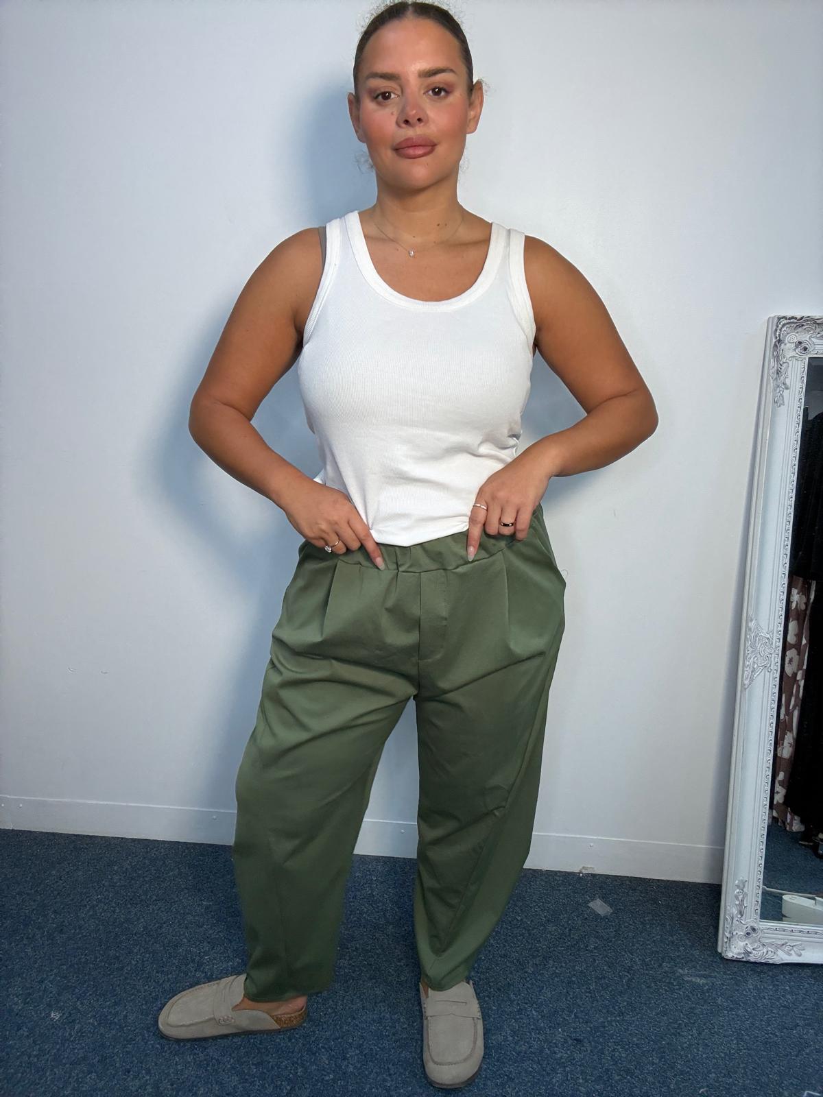 Plus-size model wearing khaki tapered trousers with an elasticated waistband, front pleat detailing and side pockets.
