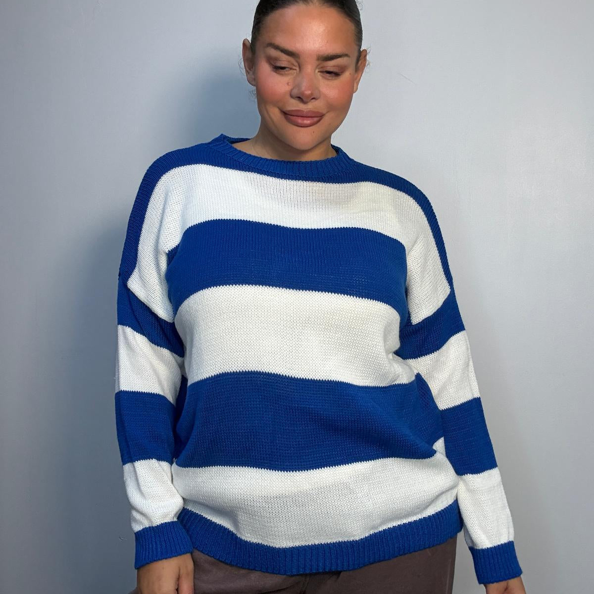 Plus-size model wearing a royal blue and white horizontally striped knitted jumper with round neckline, long sleeves and ribbed trims.