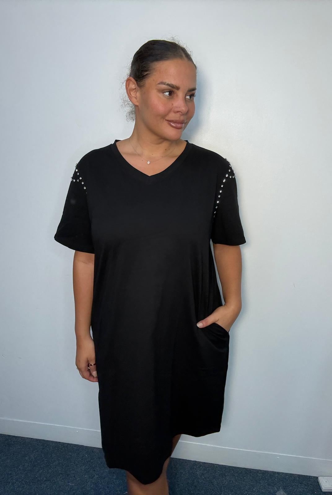 Plus-size model wearing a chocolate black V-neck midi dress with short sleeves, sparkling shoulder embellishments and relaxed fit.