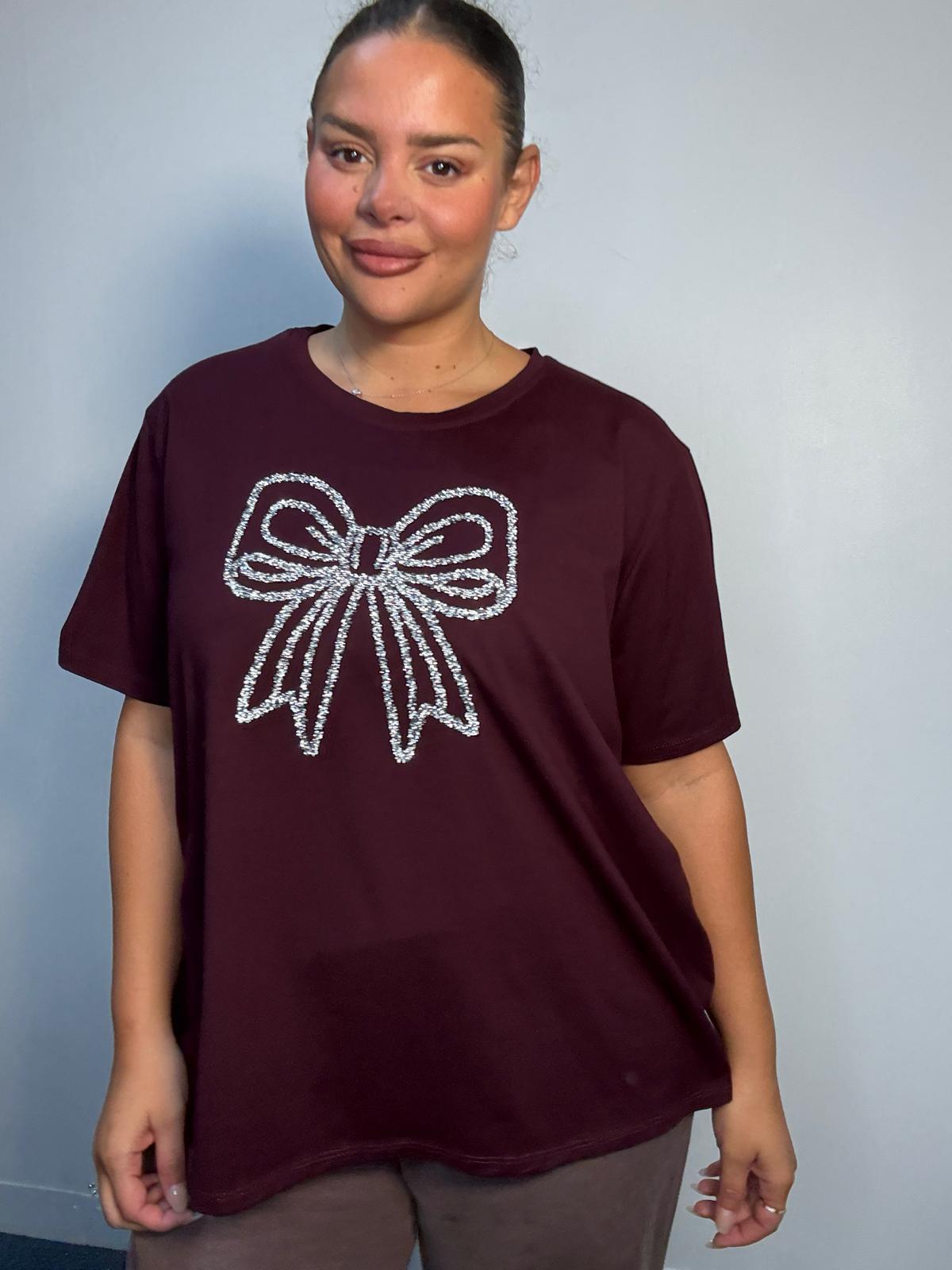 Plus Size Mixed Race Model wearing a burgundy short sleeve top with bow diamante detail at the front