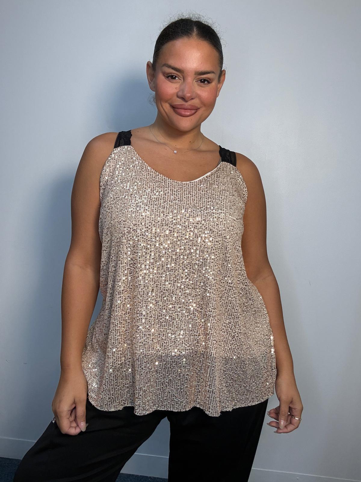 Plus-size model wearing a champagne gold sequin cami top with V-neckline, black lace-look shoulder straps and a relaxed flared hem.