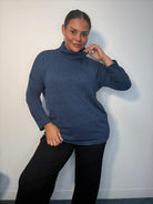 Plus-size model wearing a blue cowl neck long sleeve top with a relaxed fit.