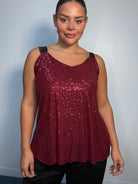 Plus-size model wearing a burgundy sequin cami top with V-neckline, black lace-look shoulder straps and a relaxed flared hem.