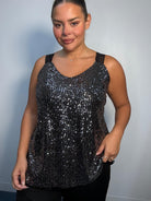 Plus-size model wearing a black and silver sequin cami top with V-neckline, black lace-look shoulder straps and a relaxed flared hem.