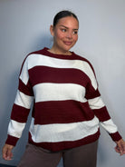 Plus-size model wearing a burgundy and white horizontally striped knitted jumper with round neckline, long sleeves and ribbed trims.