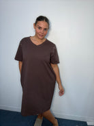 Plus-size model wearing a chocolate brown V-neck midi dress with short sleeves, sparkling shoulder embellishments and relaxed fit.