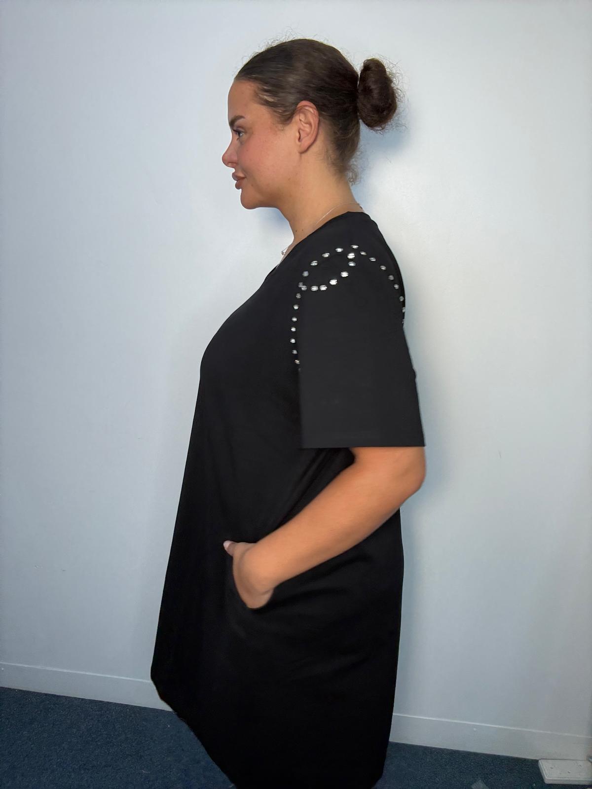 Side view of a black plus-size midi dress featuring diamante-style shoulder detailing, short sleeves and side pocket.