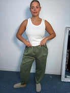 Plus-size model wearing khaki tapered trousers with an elasticated waistband, front pleat detailing and side pockets.