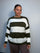Plus-size model wearing a khaki green and white horizontally striped knitted jumper with round neckline, long sleeves and ribbed trims.