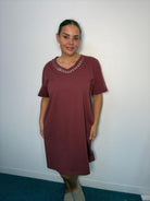 Plus-size model wearing a burgundy V-neck midi dress with sparkling neckline embellishments, short sleeves and relaxed fit.