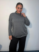 Plus-size model wearing a grey cowl neck long sleeve top with a relaxed fit.