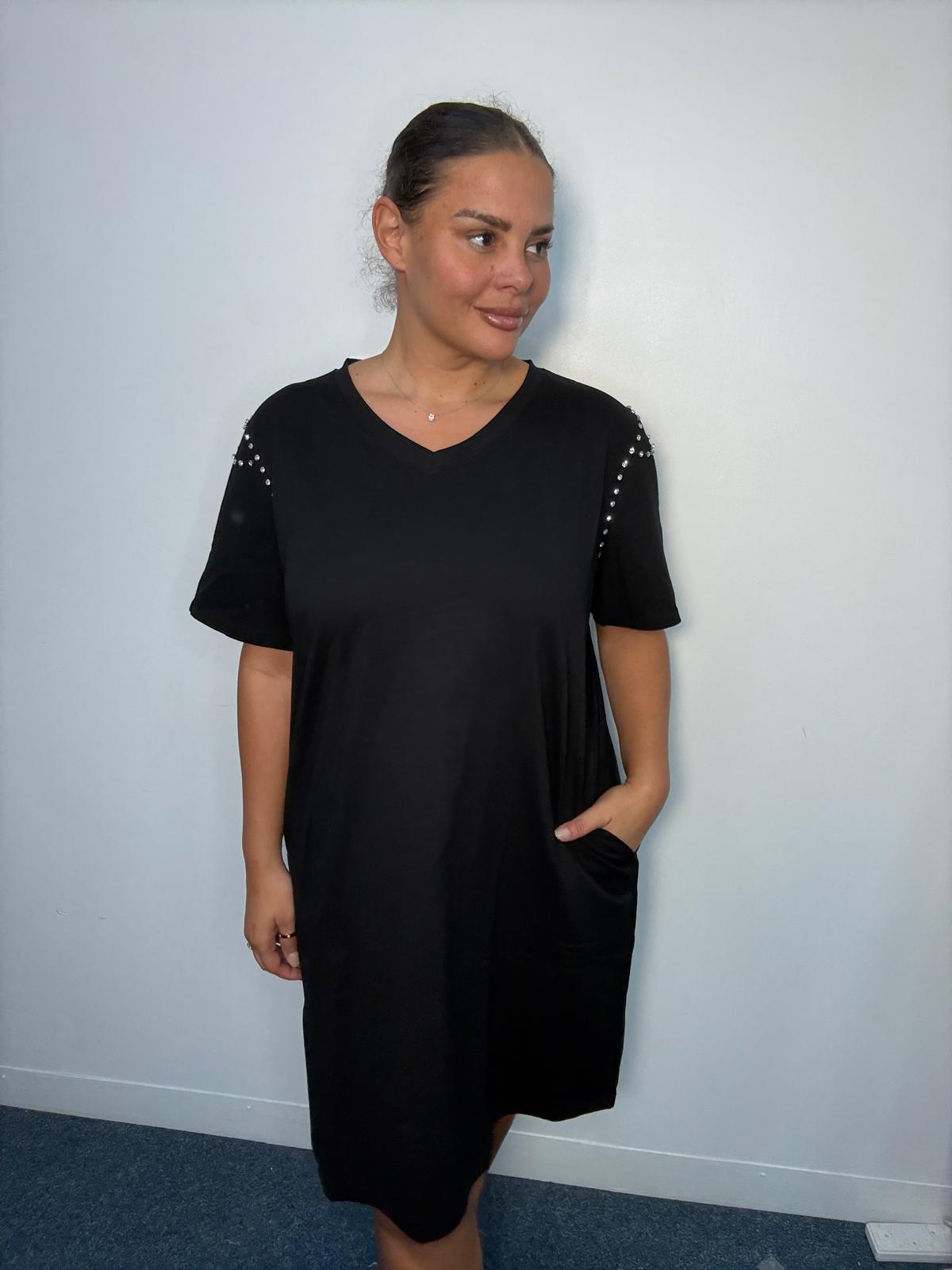 Plus-size model wearing a chocolate black V-neck midi dress with short sleeves, sparkling shoulder embellishments and relaxed fit.