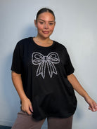 Plus Size Mixed Race Model wearing a black short sleeve top with bow diamante detail at the front