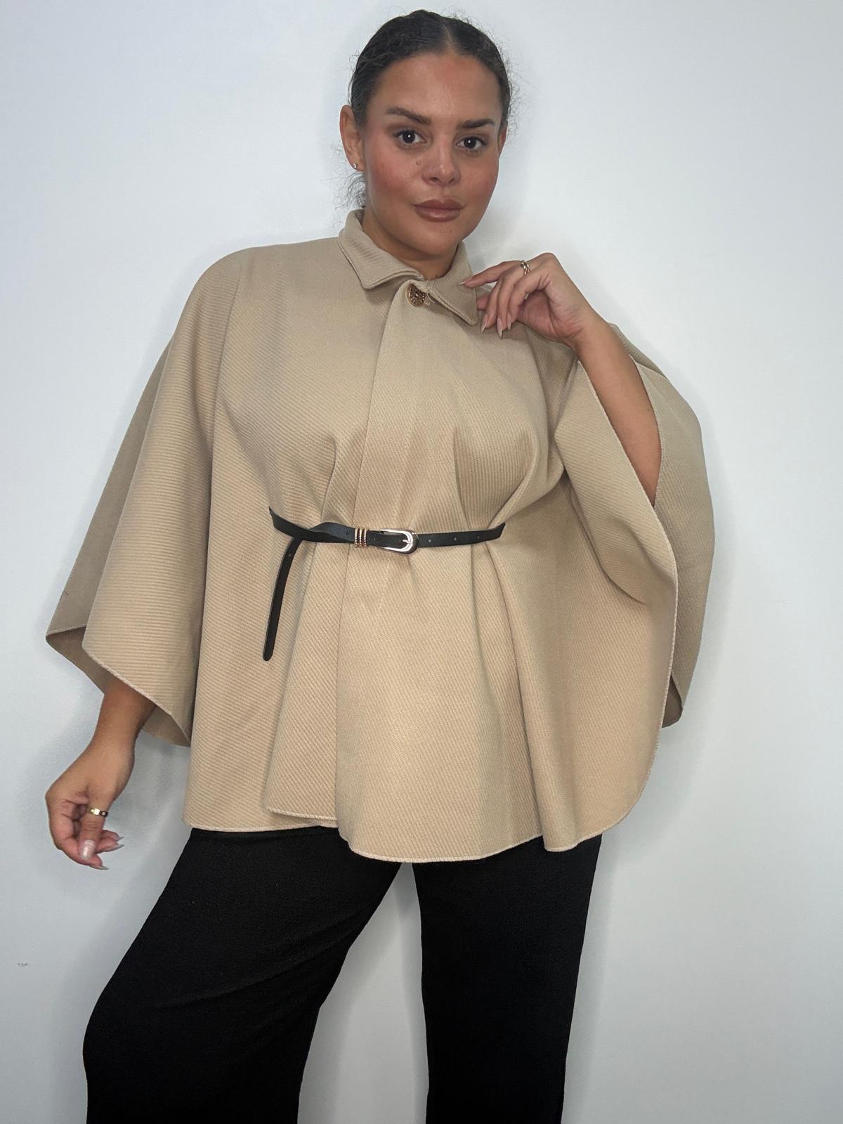 Plus-size model wearing a beige belted cape-style jacket with a high neckline and wide sleeves.