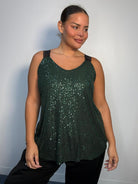 Plus-size model wearing a green sequin cami top with V-neckline, black lace-look shoulder straps and a relaxed flared hem.