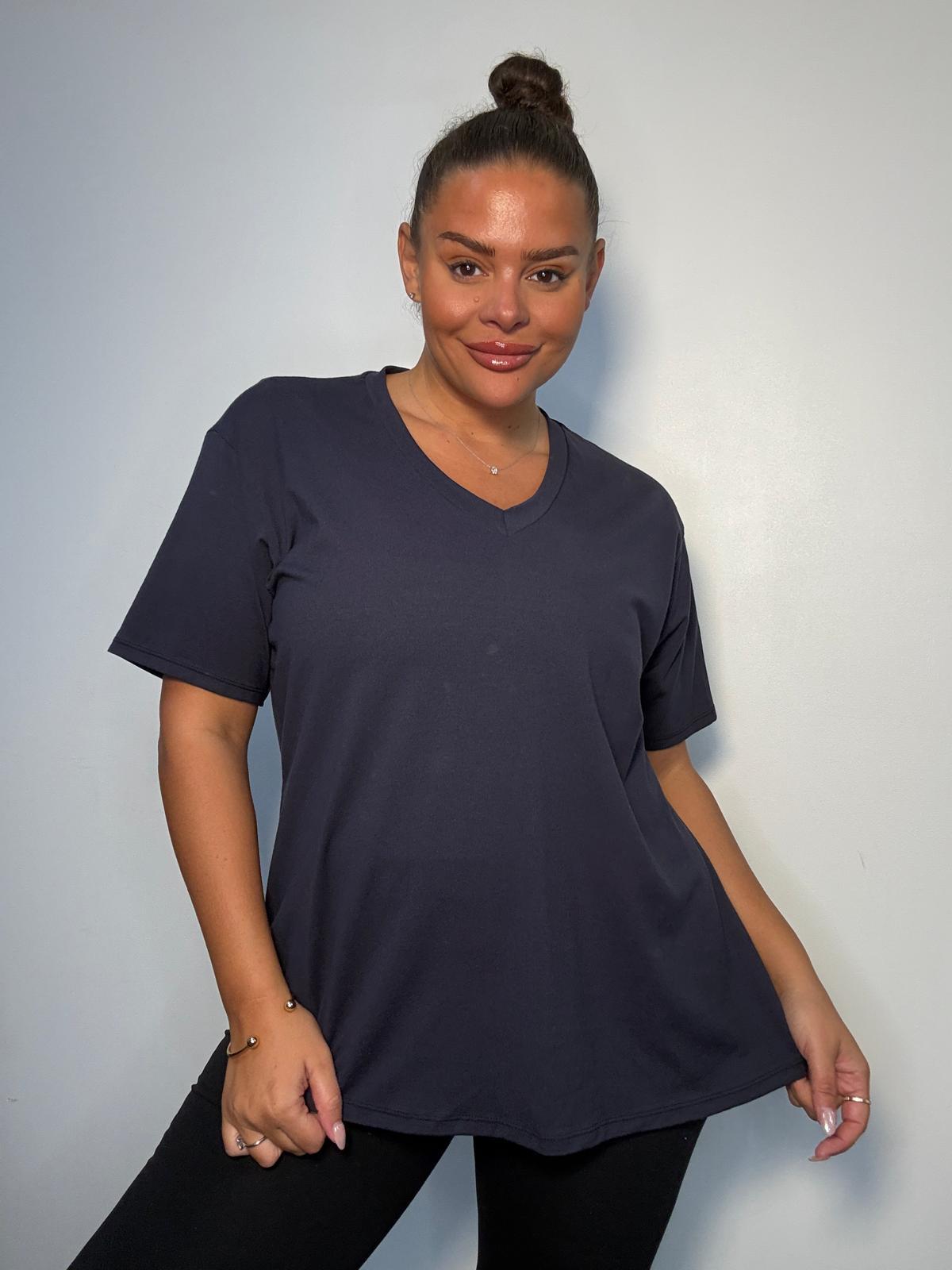 Model wearing a navy plus size V-neck T-shirt with short sleeves and a relaxed fit, styled with black trousers.