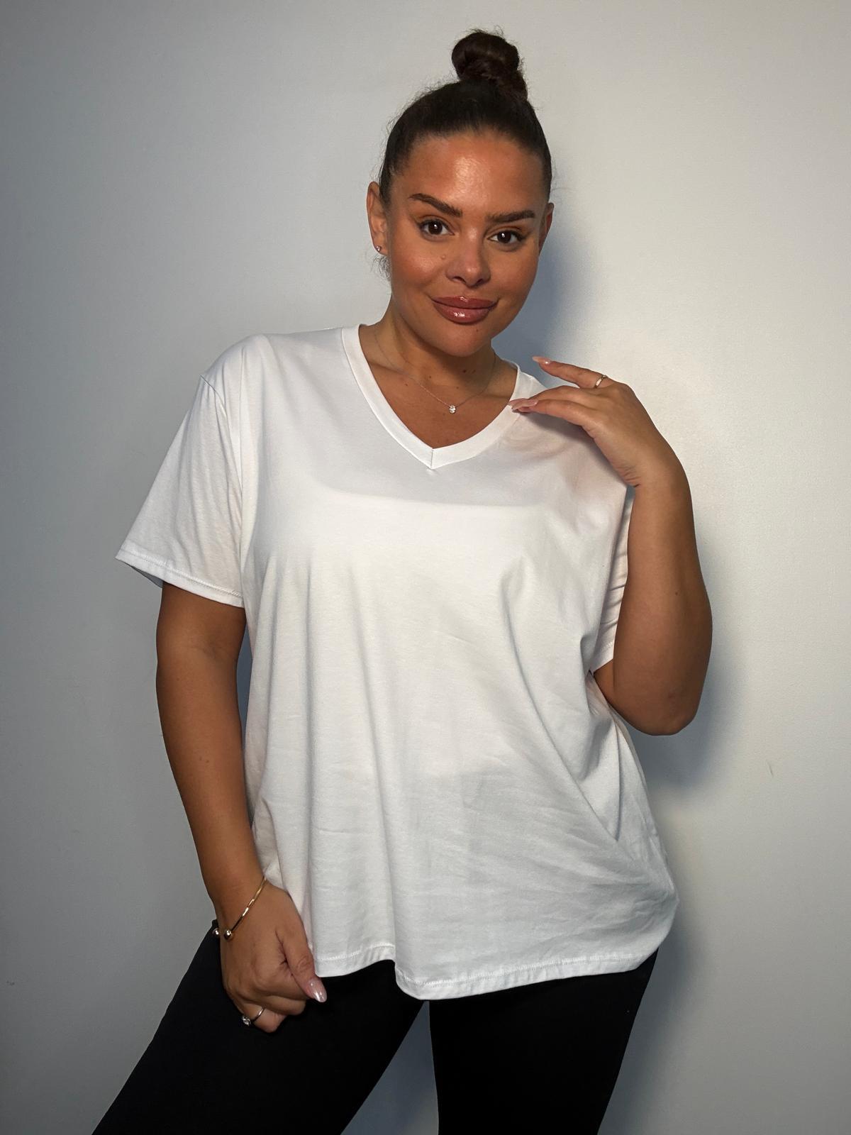 Model wearing a white plus size V-neck T-shirt with short sleeves and a relaxed fit, styled with black trousers.