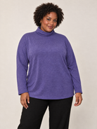 Plus-size model wearing a purple cowl neck long sleeve top with a relaxed fit.